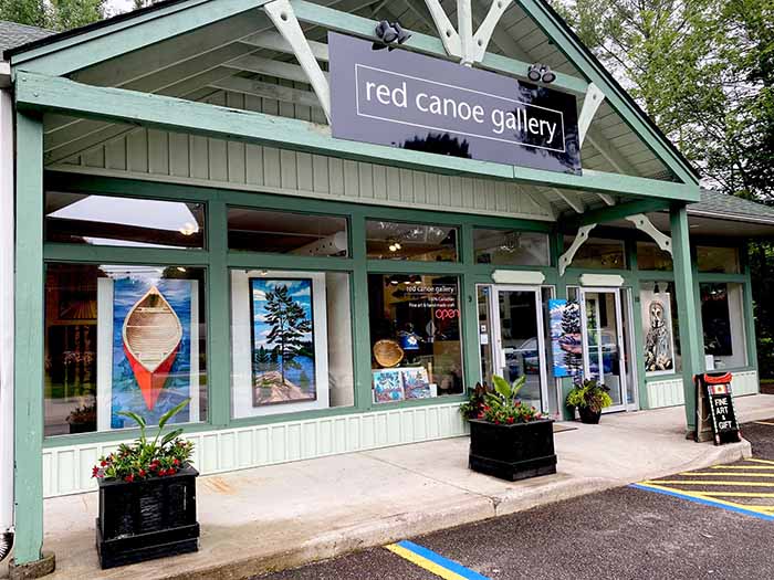 The front of Red Canoe Gallery. Elegantly light green wood with large windows.